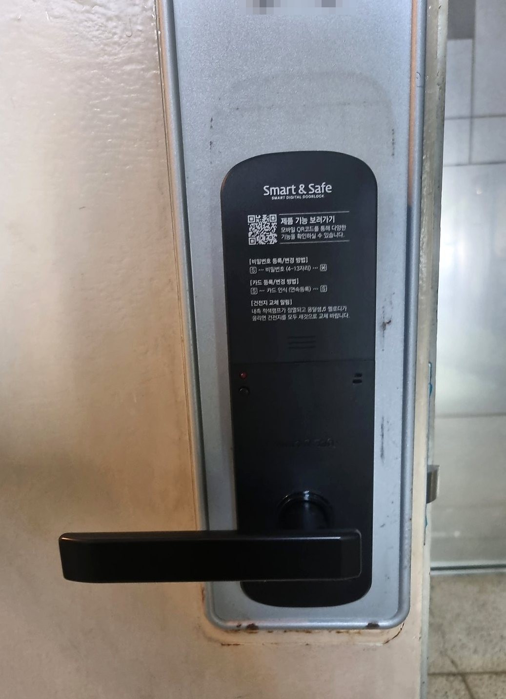 서초구 양재1동 출장 — 은회색 판 위에 단 검은 레버형 도어락 본체와 윗면의 QR 표시